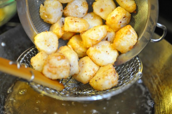 Using the strainer and spider to carefully transfer the scallops into the oil